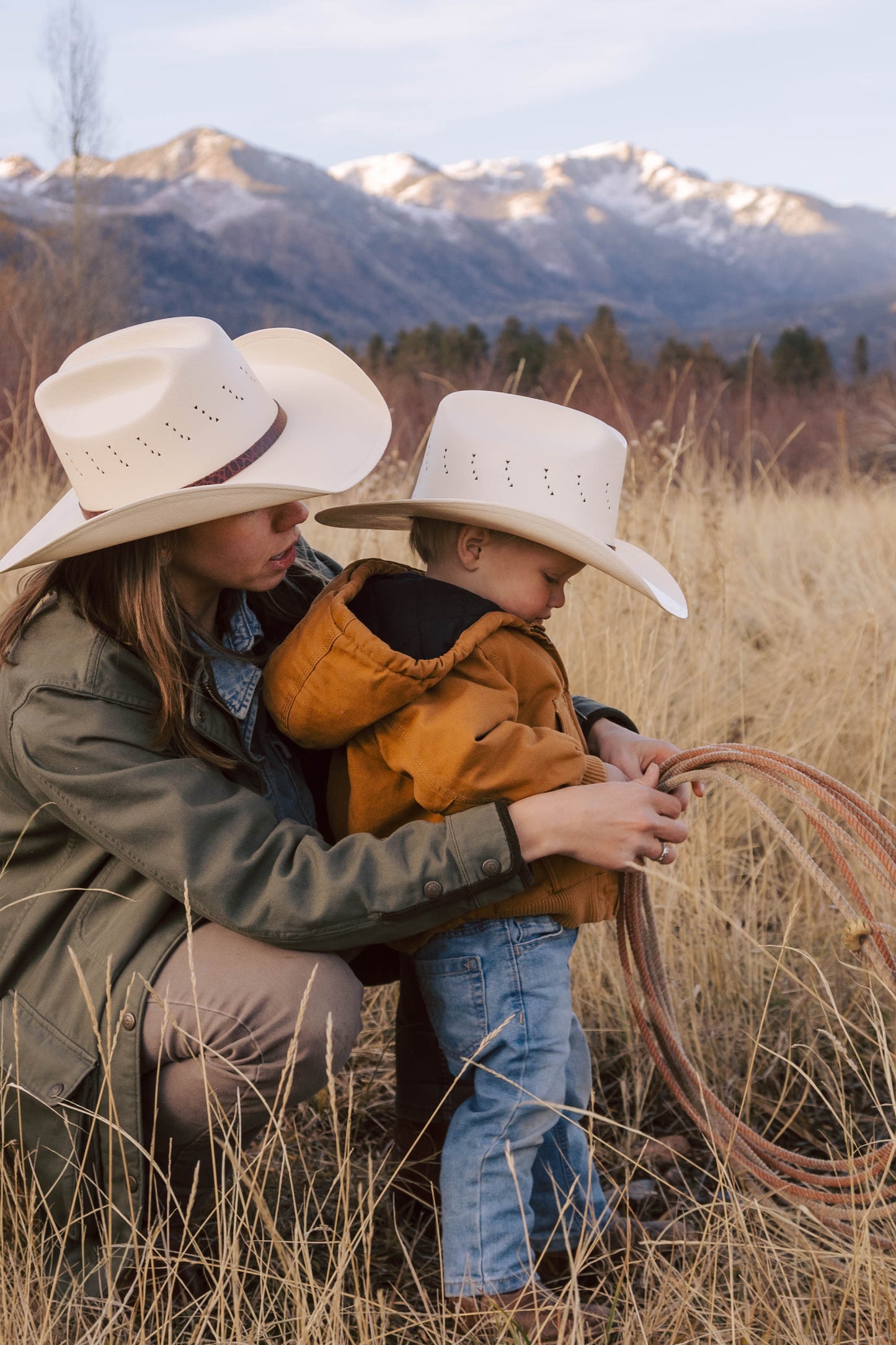 Woman and child wearing Turner Hat Cowboy Canvas hats in a field with mountains in the background